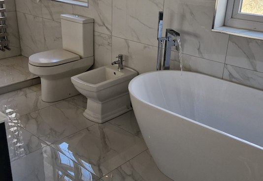Marble bathroom with a freestanding bath by AG Signature Renovation