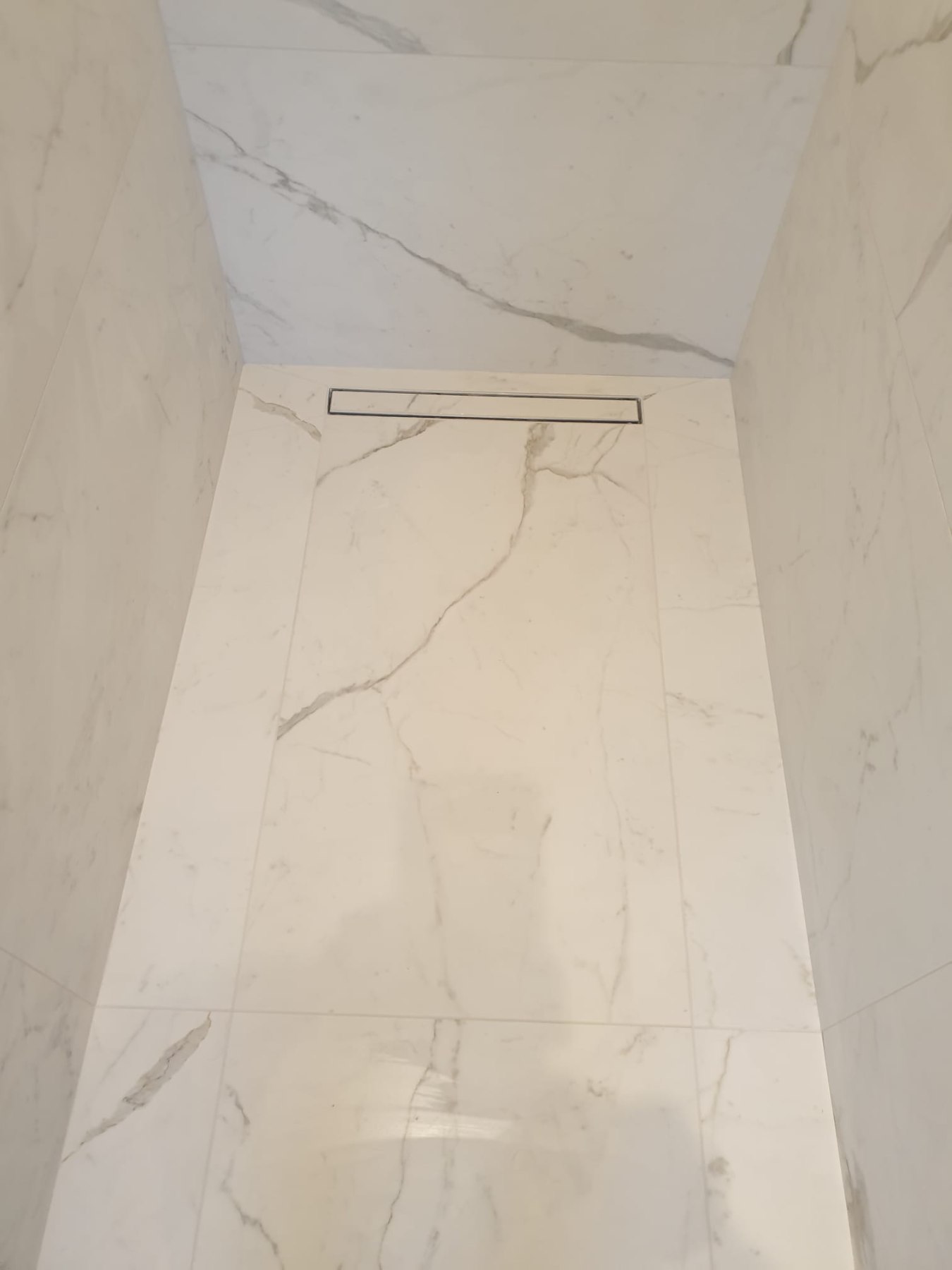 Calacatta shower floor with linear drain by AG Signature Renovation